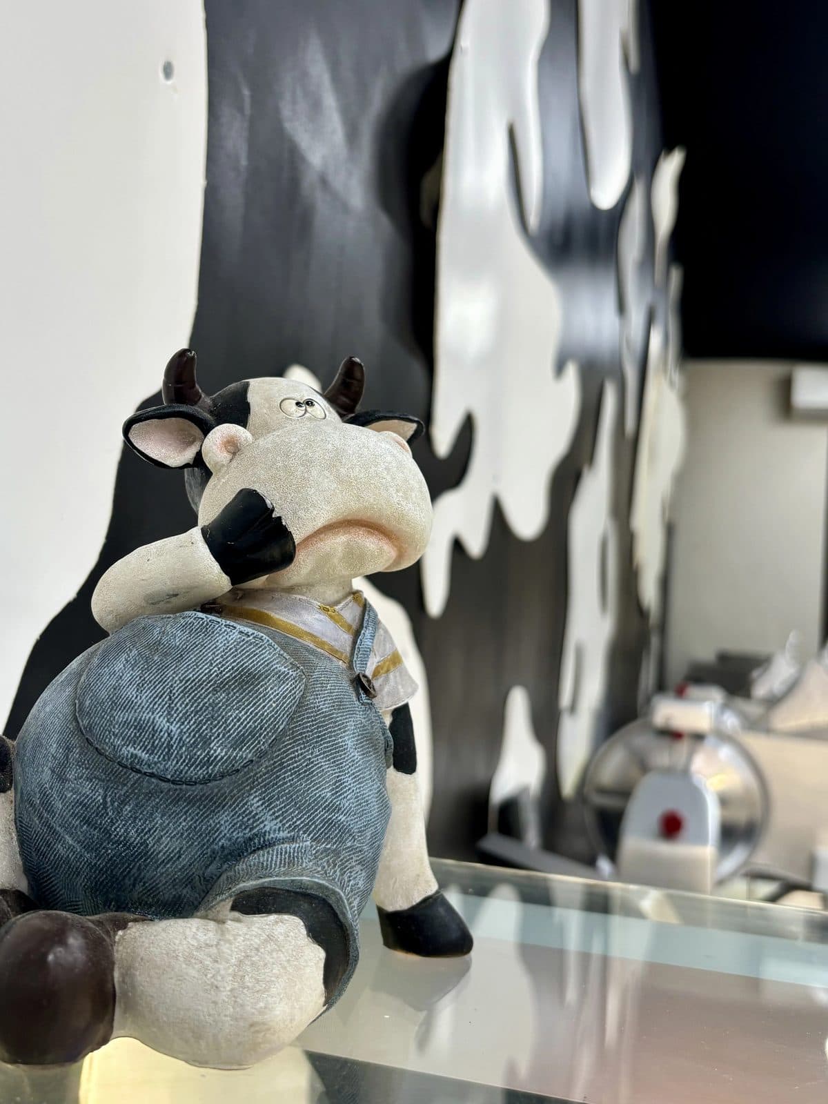 La statuette de vache du magasin, en salopette, posée près de la vitrine